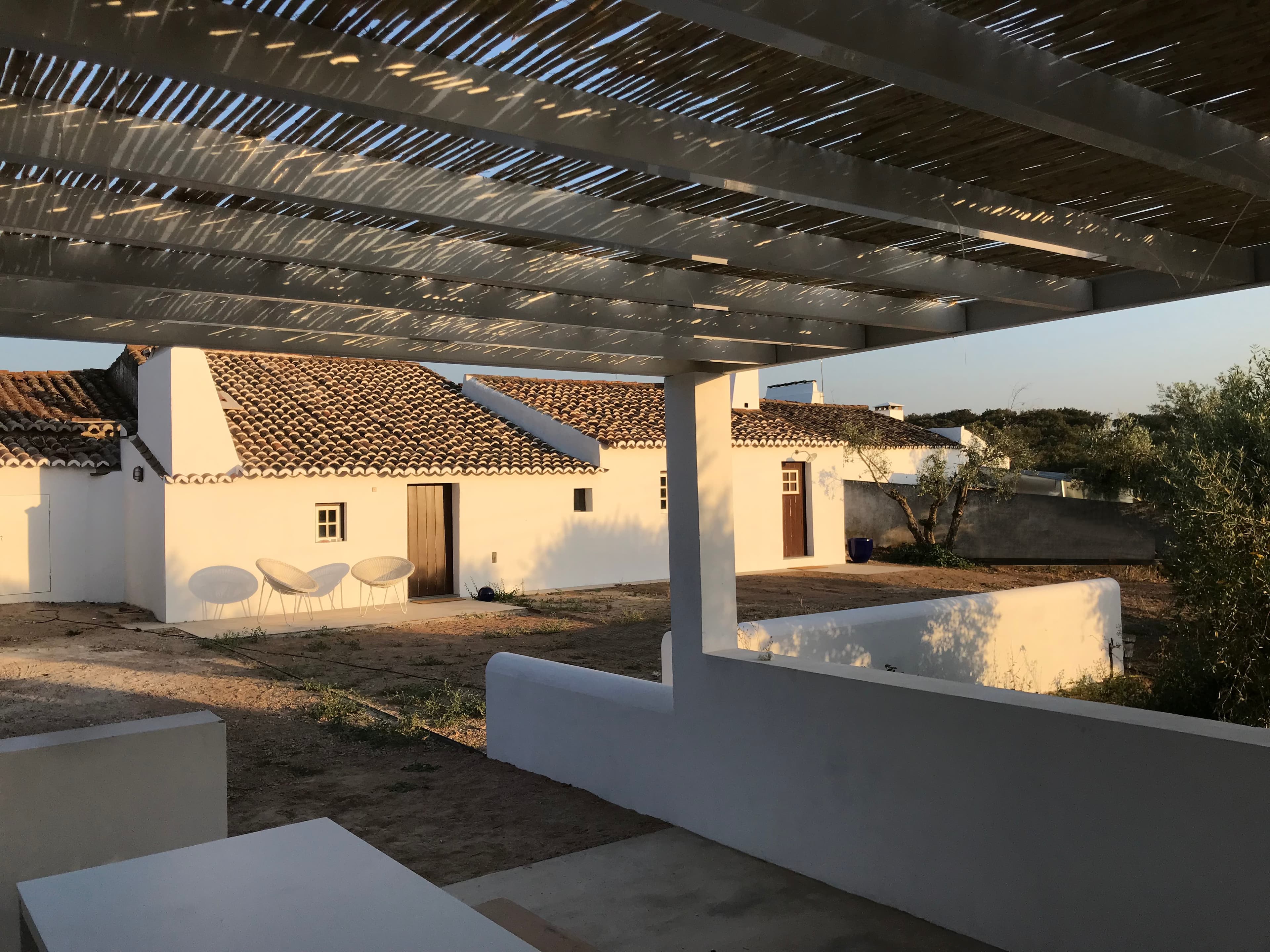 White Mediterranean-style buildings with terracotta roofs under slatted pergola