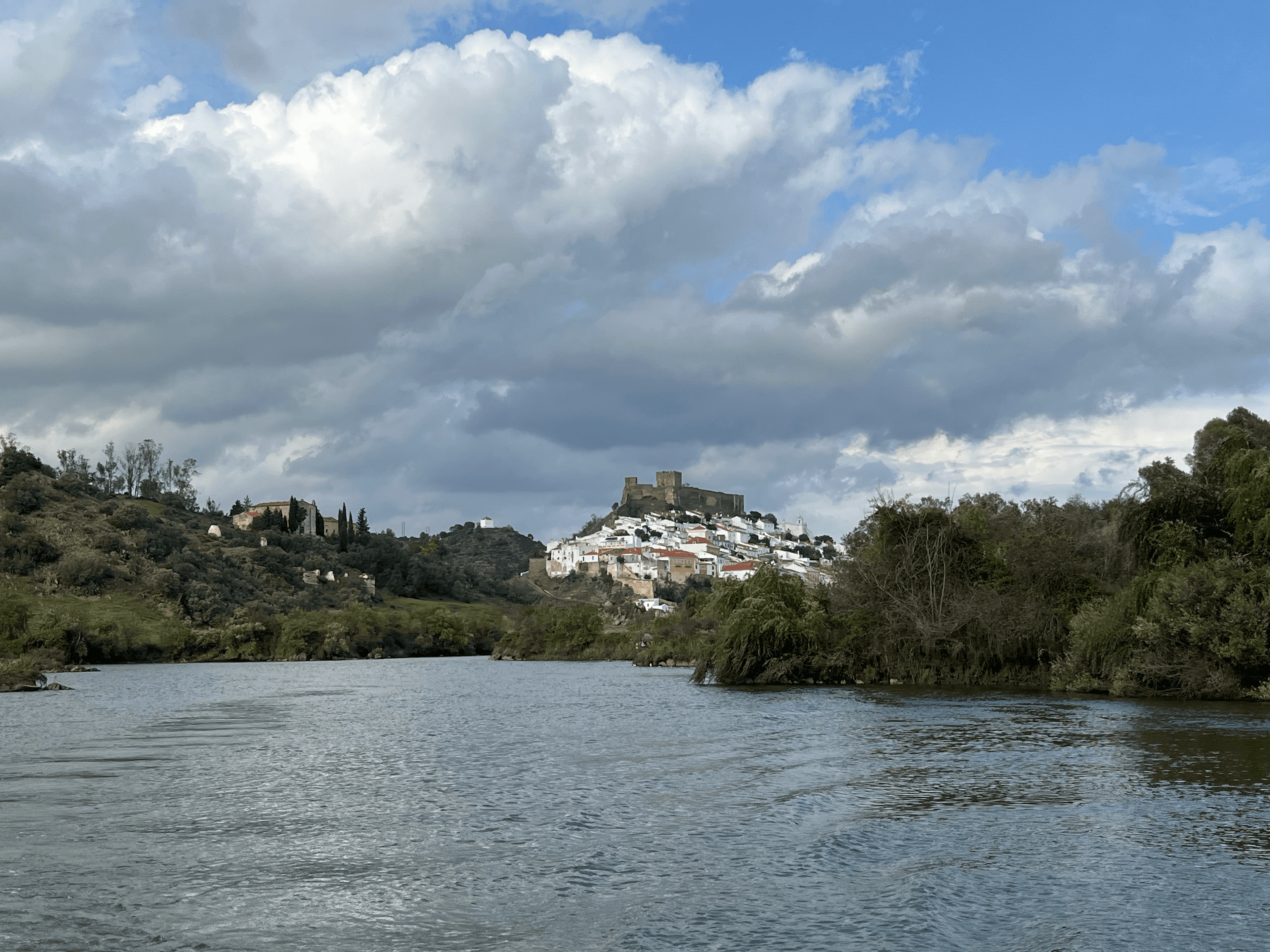 Panoramic view of historic white-walled town and stone castle on a hill above a river