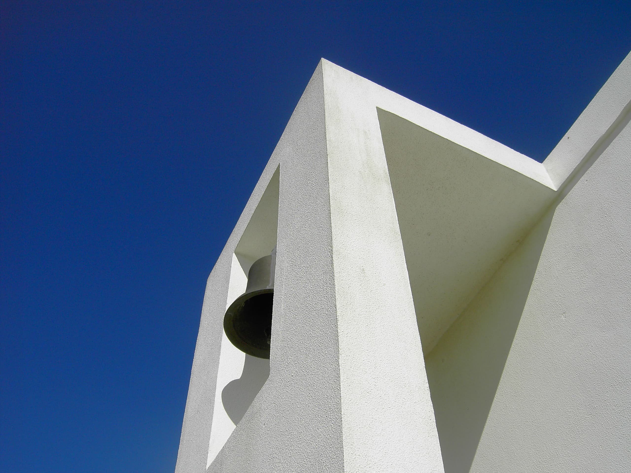 Modern architectural structure with bell tower against clear blue sky